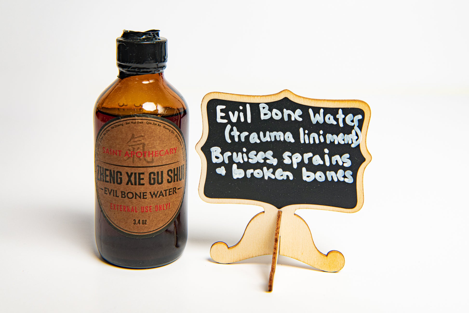 Evil Bone Water Photo with sign that says trauma liniment, bruises, sprains and broken bones, photo credit by Laura Orozco Photography